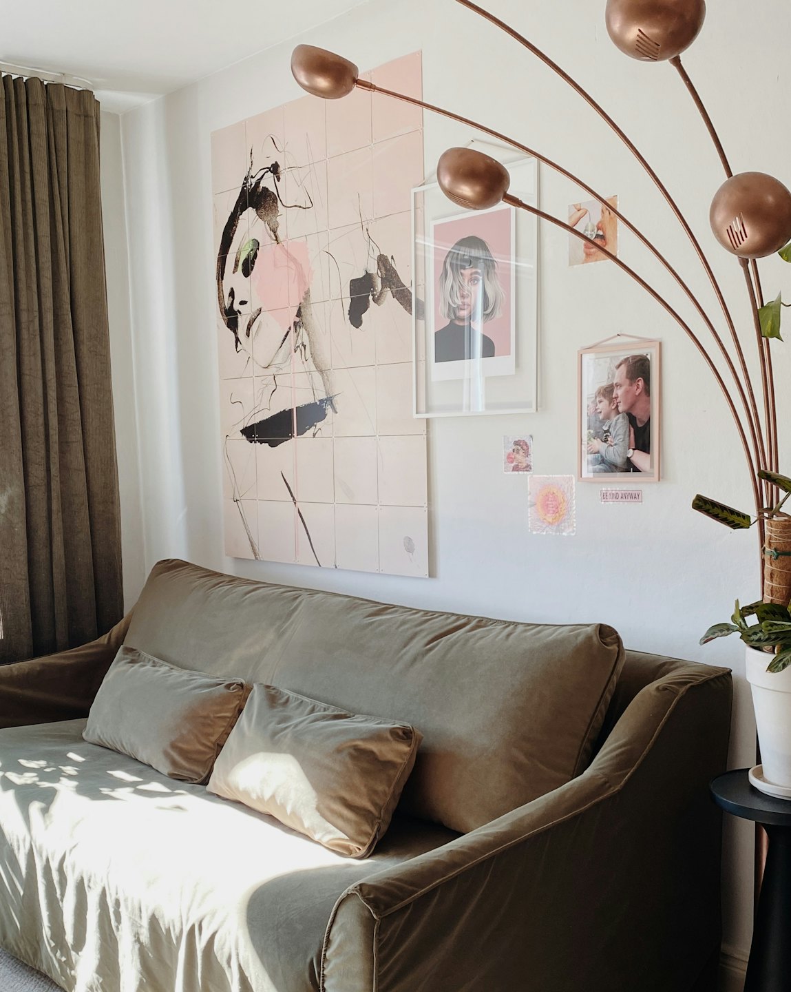 Sage green velvet sofa in a sunlit living room.